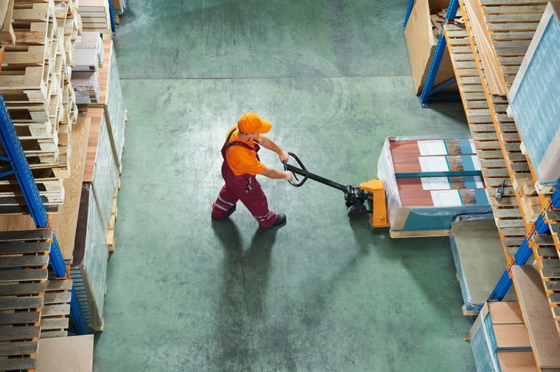 Overhead view of a warehouse worker pushing a pallet truck