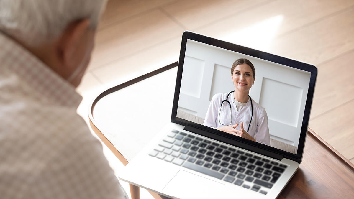 Close up of modern elderly man sit at home having online consultation with doctor on computer