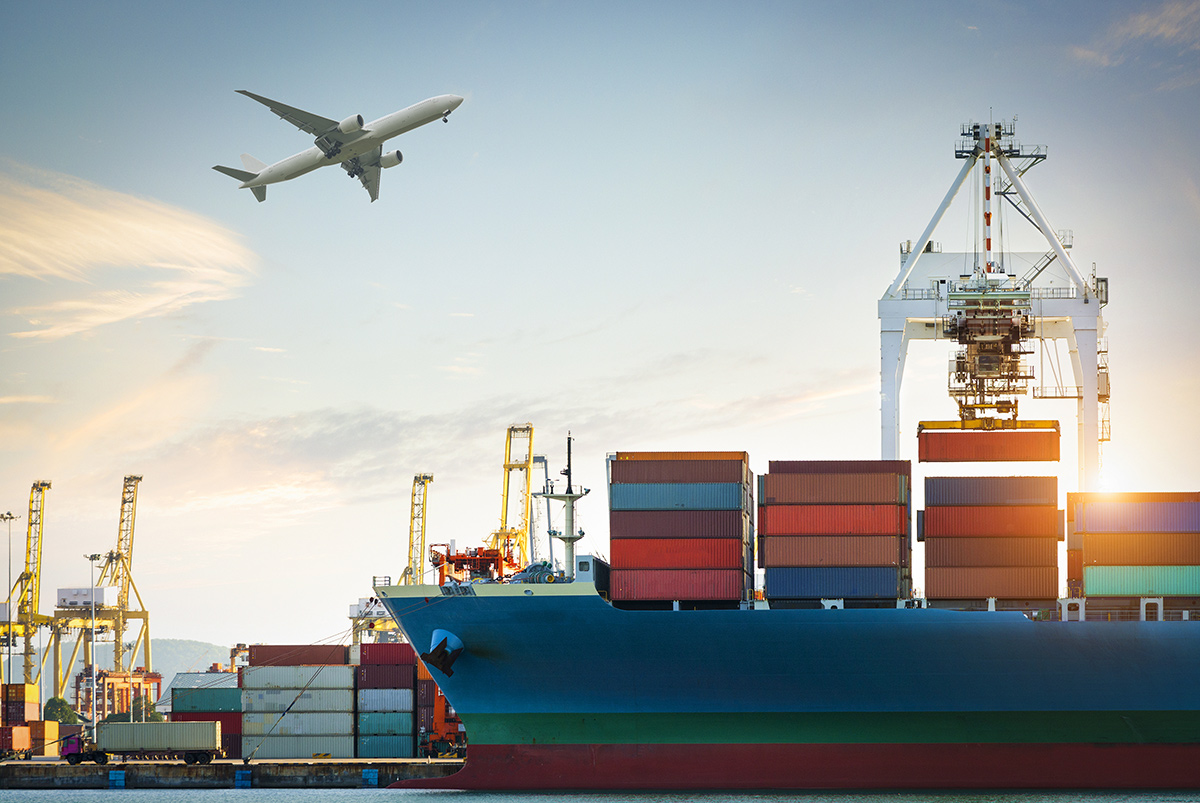 Container cargo ship at trade port with an airplane flying overhead