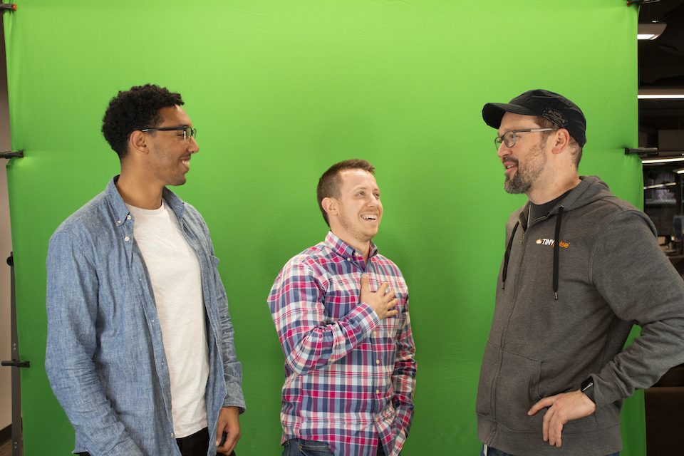 TINYPulse team chatting in front of green screen