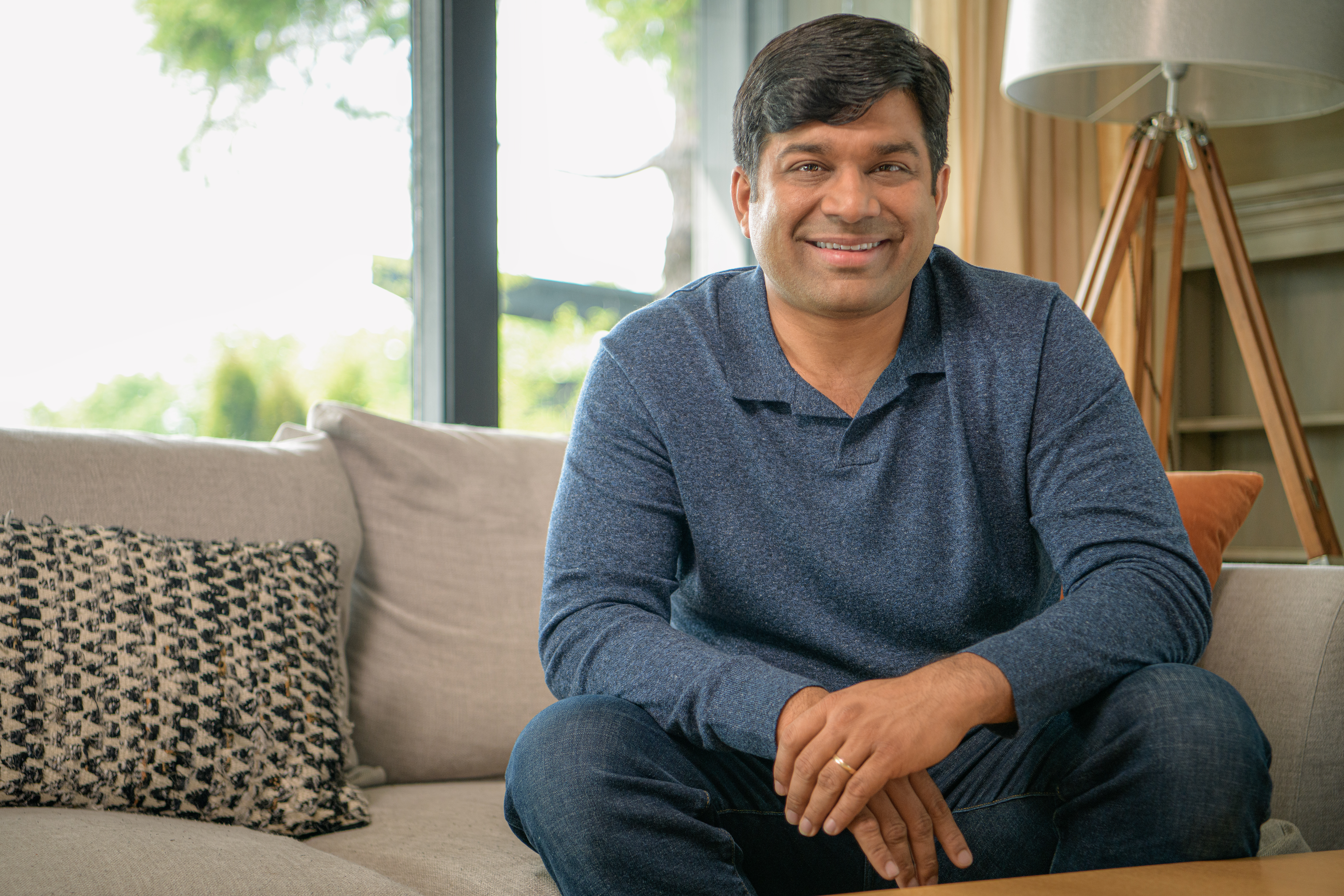 Co-founder Tushar Garg sitting on a couch and smiling into the camera.