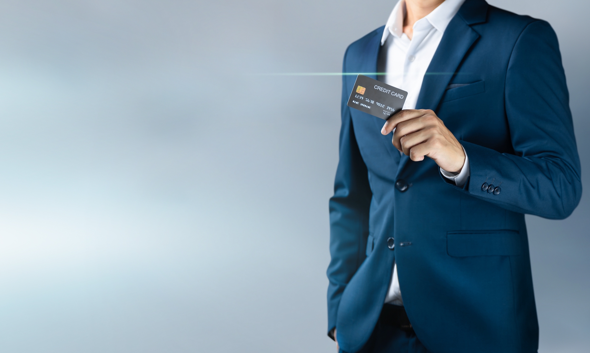 A businessman is pictured holding up a credit card.
