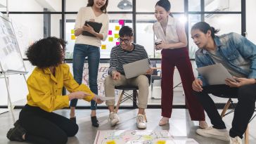 Image of five coworkers collaborating together in their office