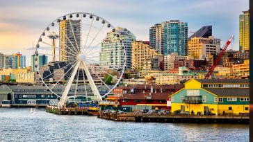 Seattle waterfront and skyline, with the Space Needle showing through the spokes of the Great Wheel ferris wheel in the foreground