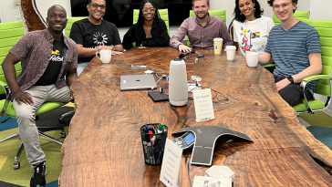 Fetch employees smile at the camera from around a conference table.