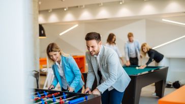 Coworkers playing a foosball table in an office.