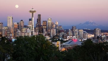 The Seattle skyline with a full moon and Mt. Rainier in the backdrop