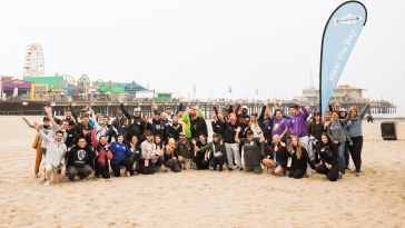 Large group photo of WB Discovery team members at a Heal the Bay event on the beach