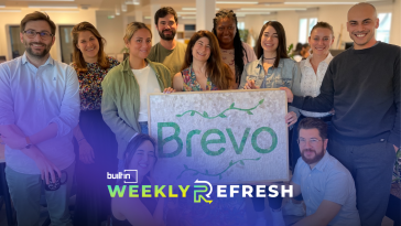 The Brevo team poses for a group photo holding a sign with the new company name.