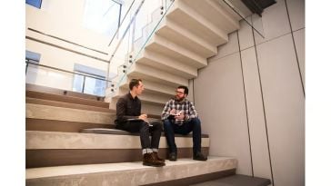 Two employees chat in the office common area.