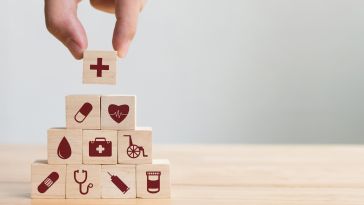 A person stacking blocks with healthcare symbols on them is shown.